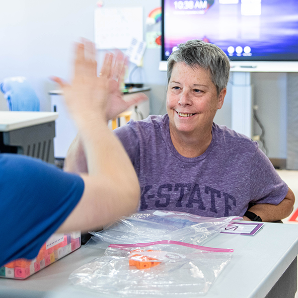 Lisa Jones high-fiving a student while working on a matching assignment.